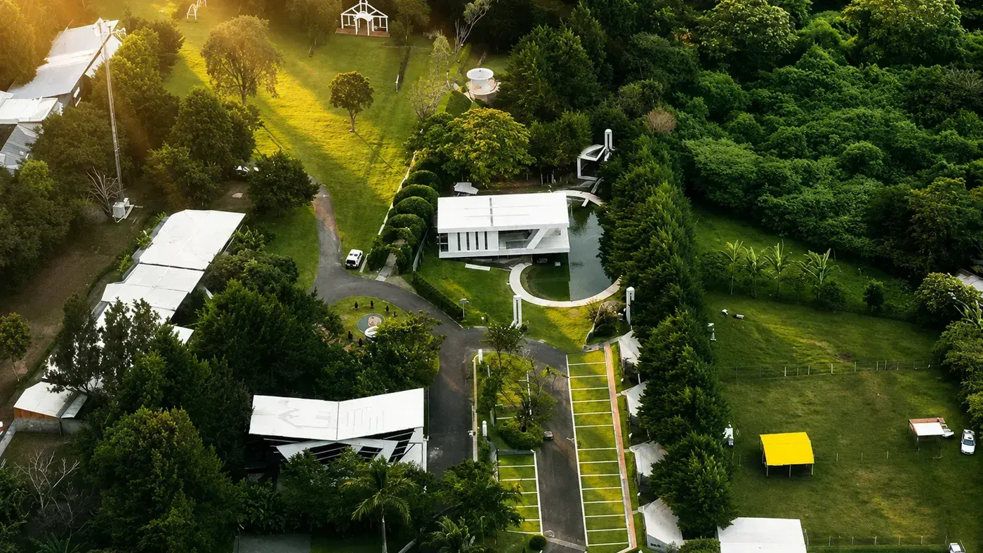 Vista aérea del complejo: la fachada estilo iglesia sobre el prado, el gazebo, el salón de Laureal y, contiguo, la arquitectura contemporánea de Nebulae con su espejo de agua