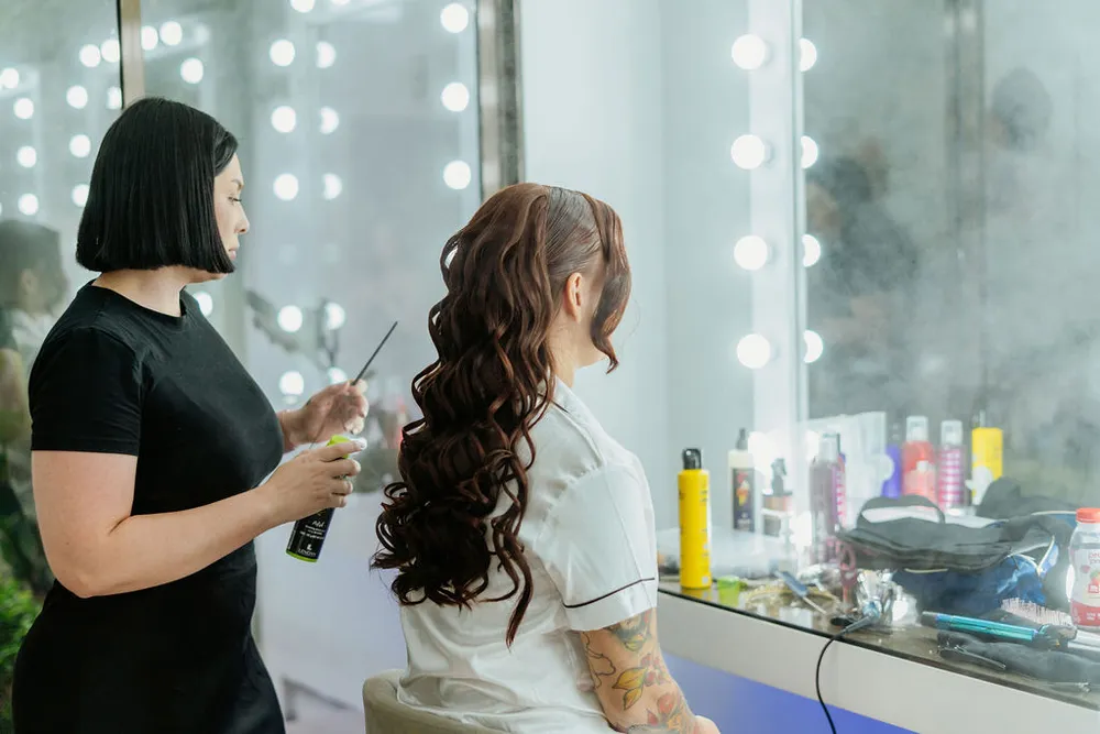 Estilista aplicando fijador al peinado de la novia en el Salón de Maquillaje
