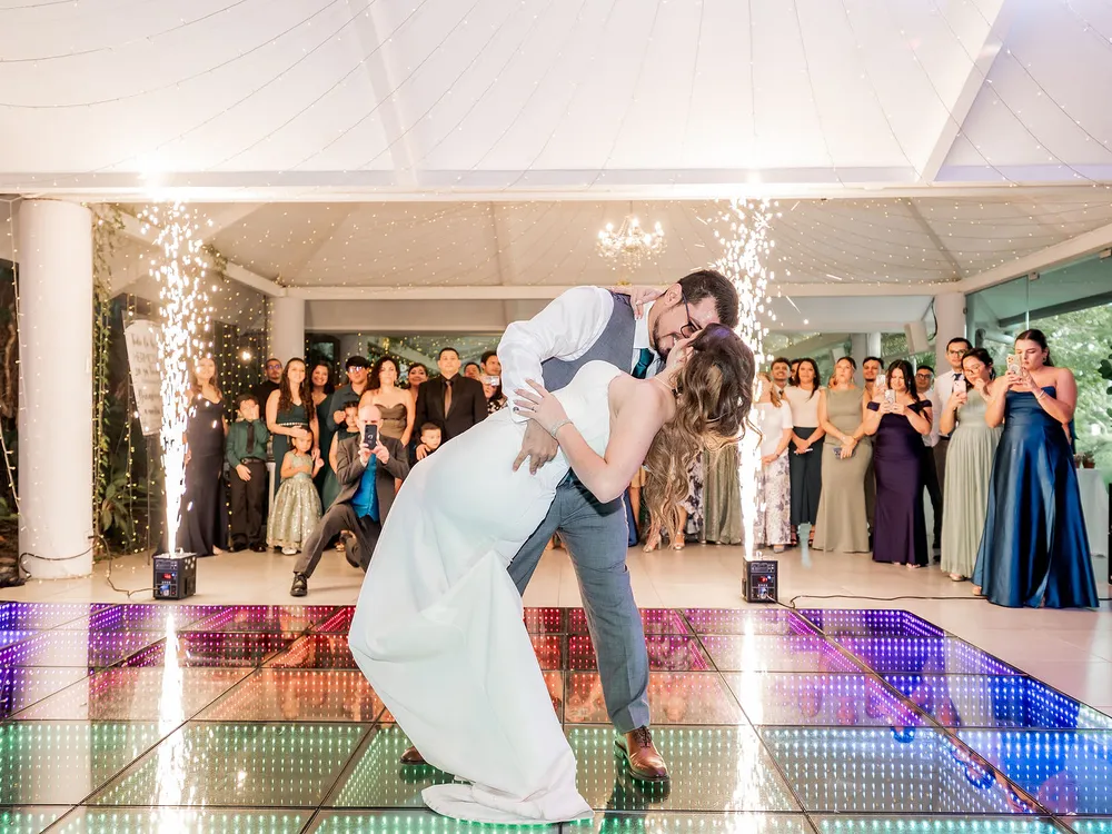 Primer baile de los novios sobre la pista LED, con chispas frías y los invitados alrededor